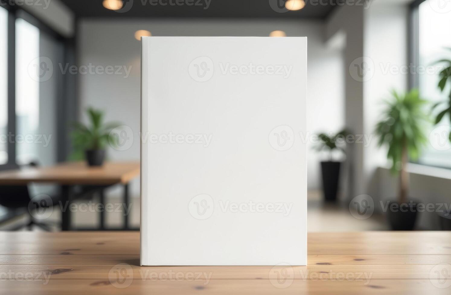 Minimalist blank book on a wooden table in a modern workspace with plants and natural light during the day photo