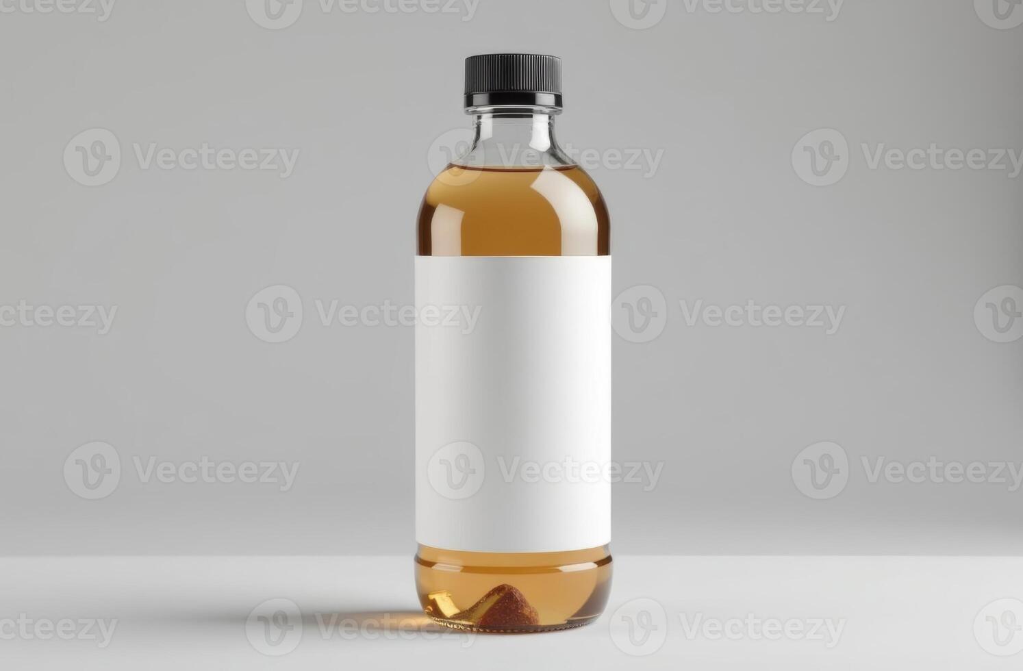 A clear bottle filled with golden liquid sits against a light gray background, featuring a blank label, perfect for branding or product design photo