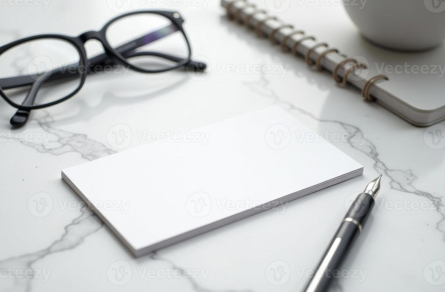 Blank business cards and stationery on a marble desk with a pen and glasses present a minimalistic workspace setup photo