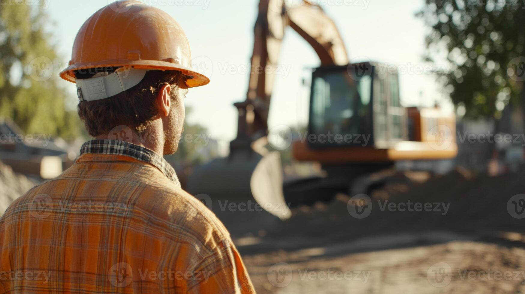 Construction worker observes heavy machinery operating at a busy construction site in the early morning sun photo
