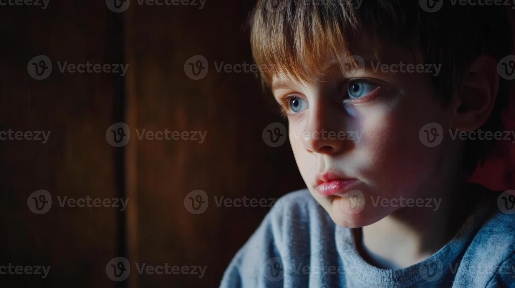 Young boy with thoughtful expression sitting indoors in soft light near window photo