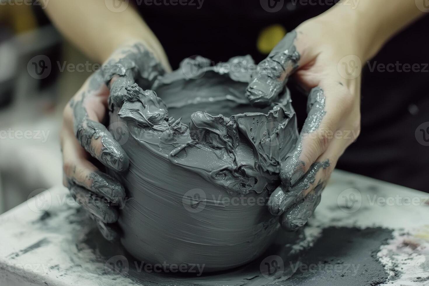 Hands shaping a gray clay pot at a pottery studio during an afternoon crafting session photo