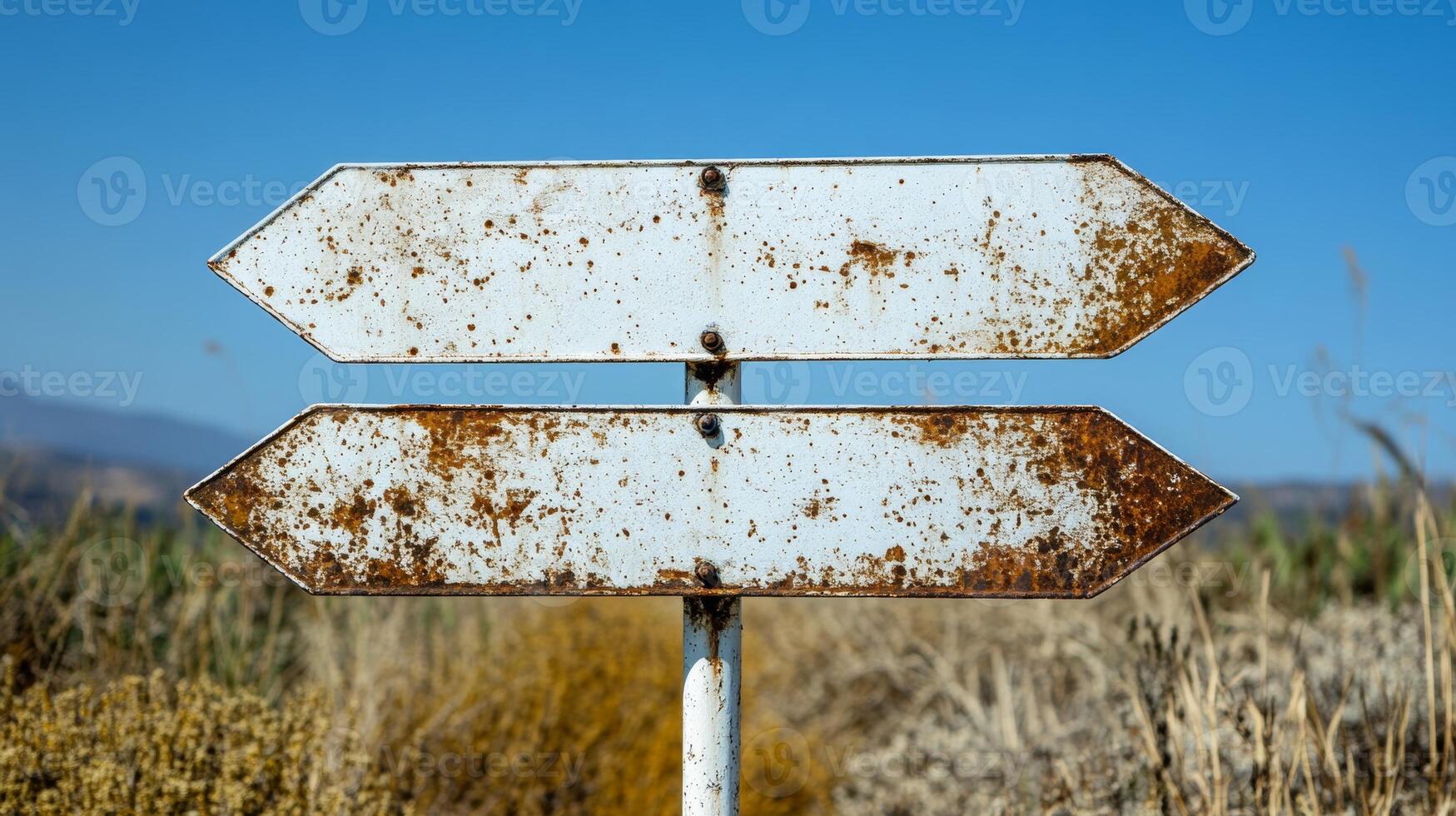 Rusty directional sign in a dry landscape, indicating multiple paths under a clear blue sky photo