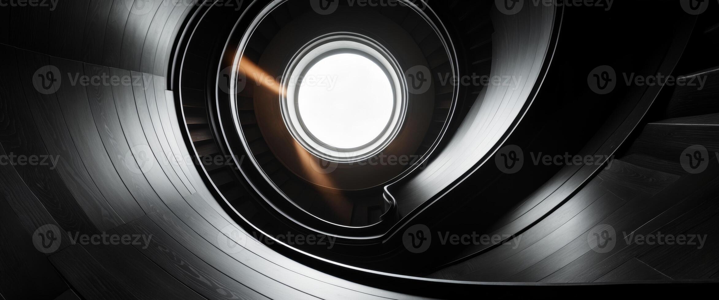 A black spiral staircase with a light shining through it photo
