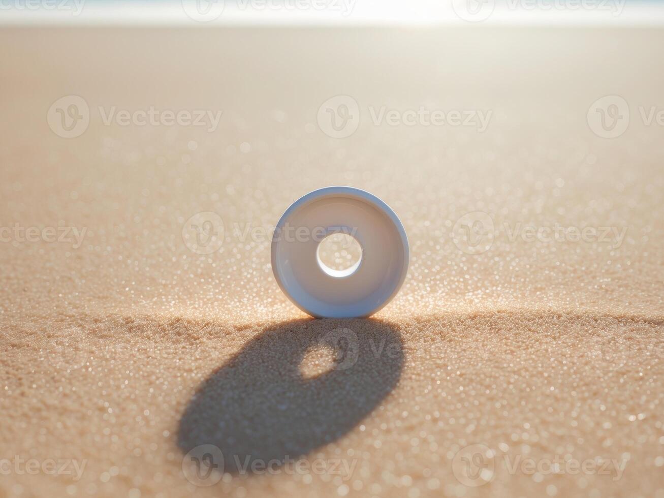 White Ceramic Donut Object Resting on a Sand Surface with a Shallow Depth of Field. photo