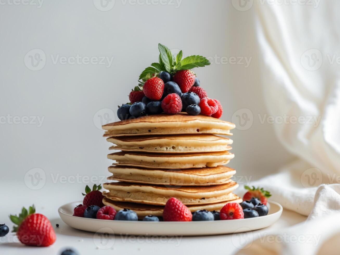 Stack of Delicious Pancakes Topped with Fresh Berries and Mint on a White Plate. photo