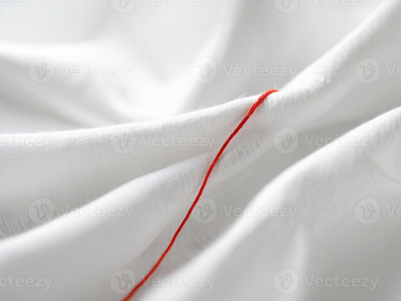 A red thread is tied to the edge of a white sheet photo