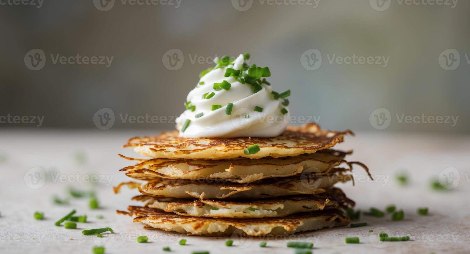 A stack of potato pancakes with sour cream and chives photo