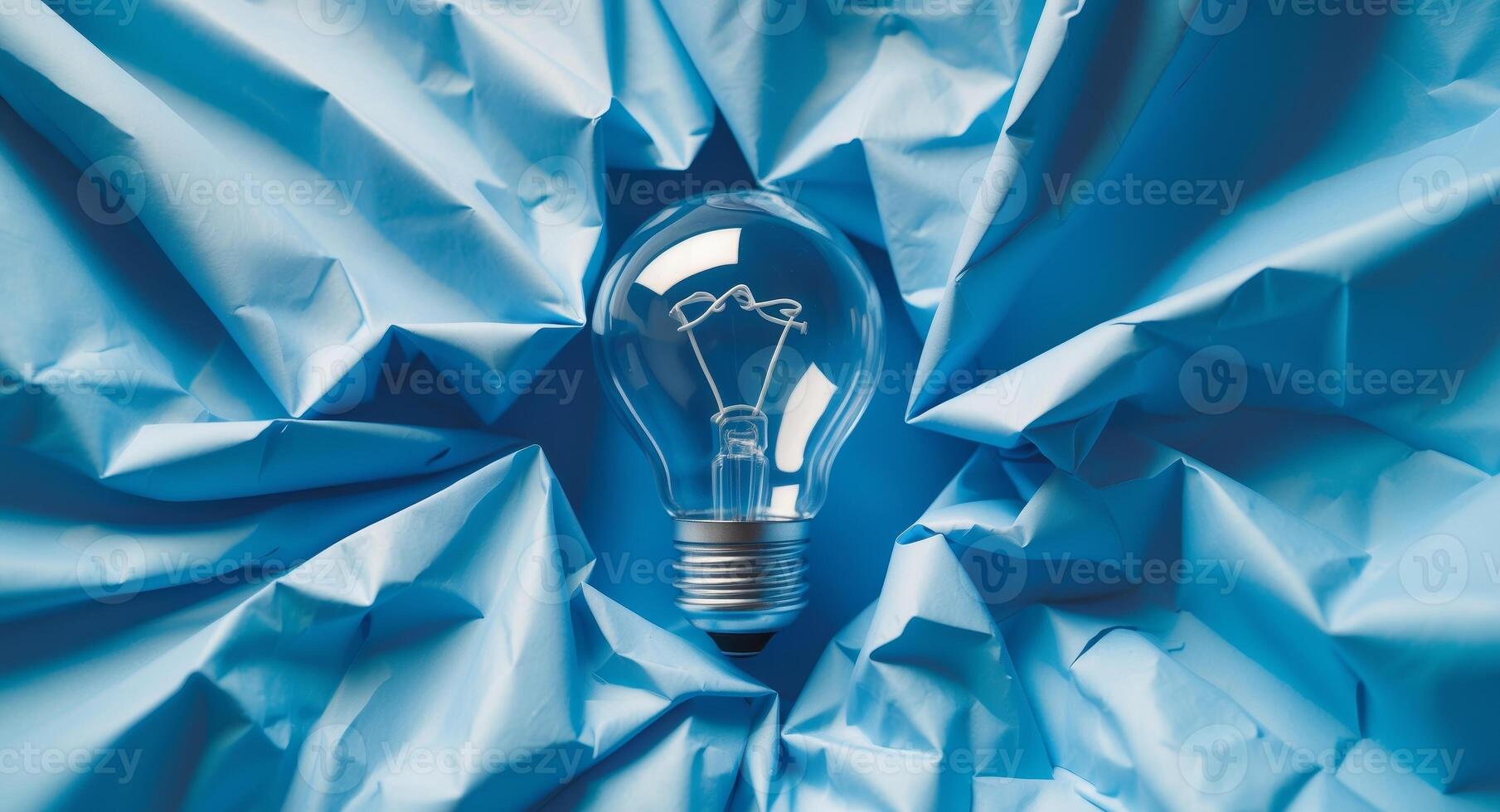 A light bulb is sitting on top of a blue crumpled paper photo