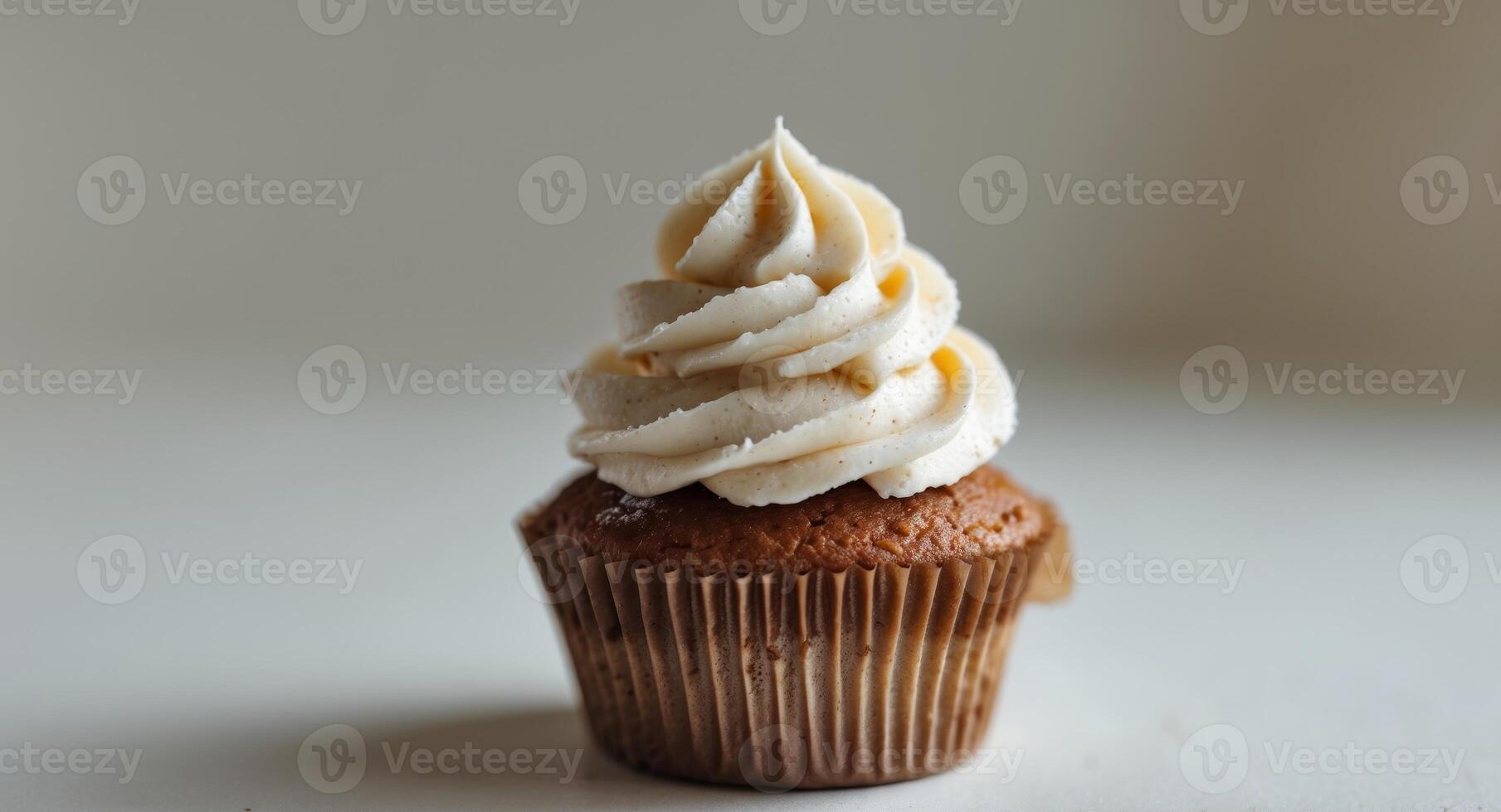 Delicious Vanilla Cupcake with Swirled Frosting, Brown Wrapper, on a Light Background photo