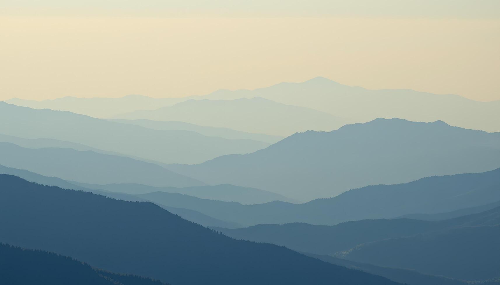 a soft haze blurs the distant ridges of a blue toned mountain range. photo