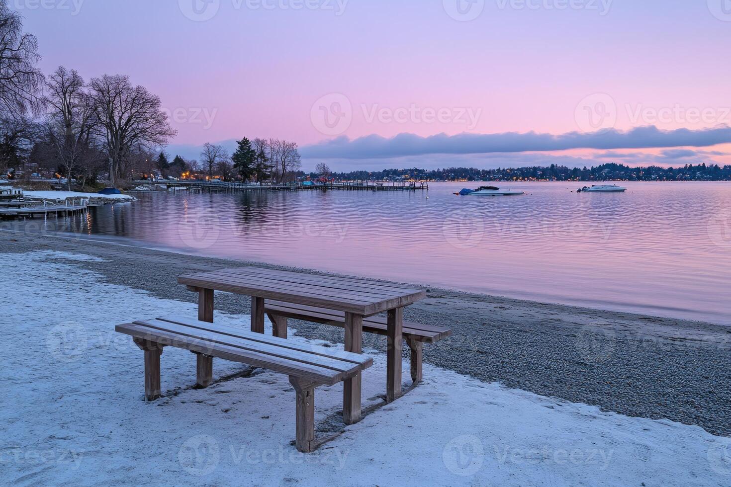 A bench and a table on a beach at sunset photo