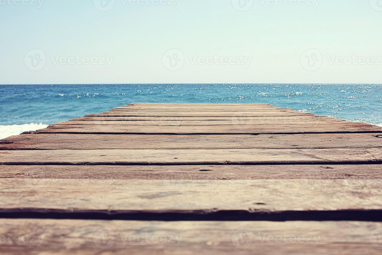 A wooden pier leads to the ocean photo