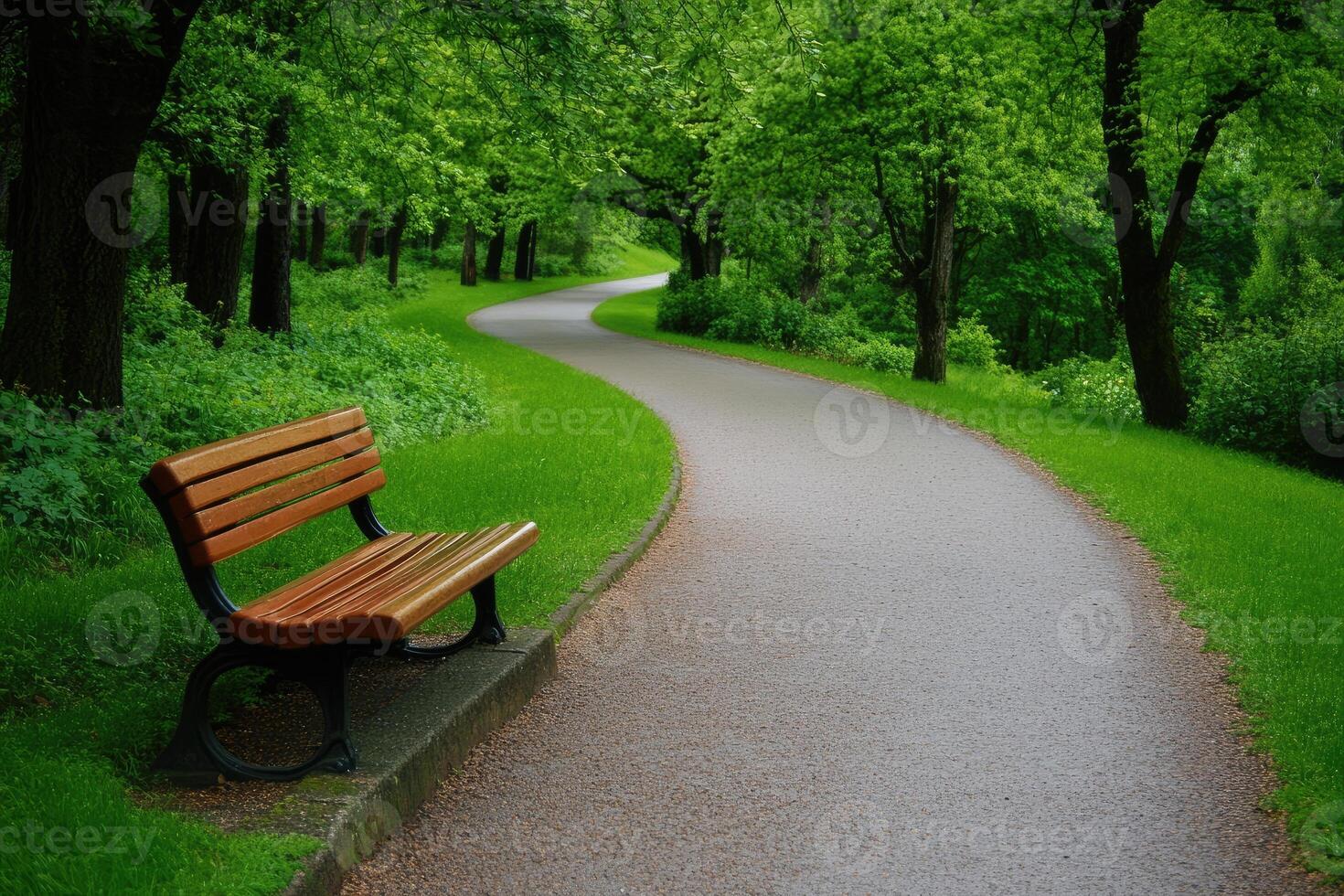 A bench sitting on a paved path next to a tree lined road photo