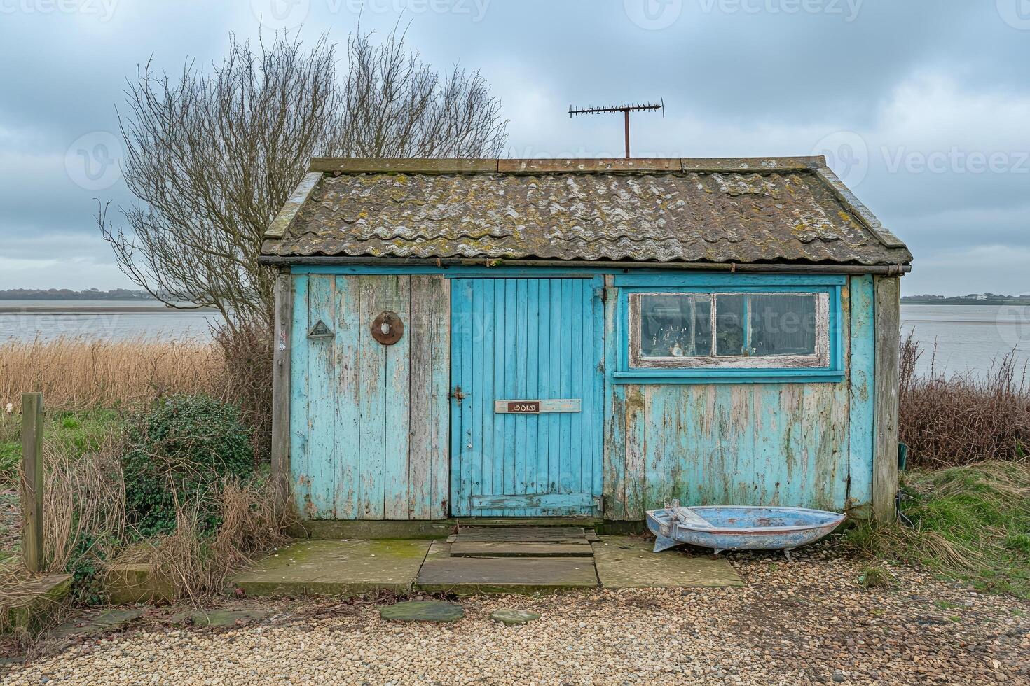 A small blue shed with a boat in front of it photo