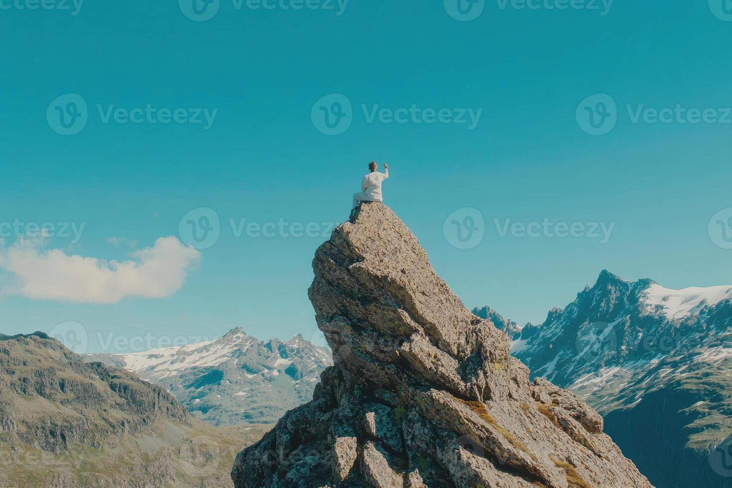 Person atop mountain peak, serene posture, expansive view photo
