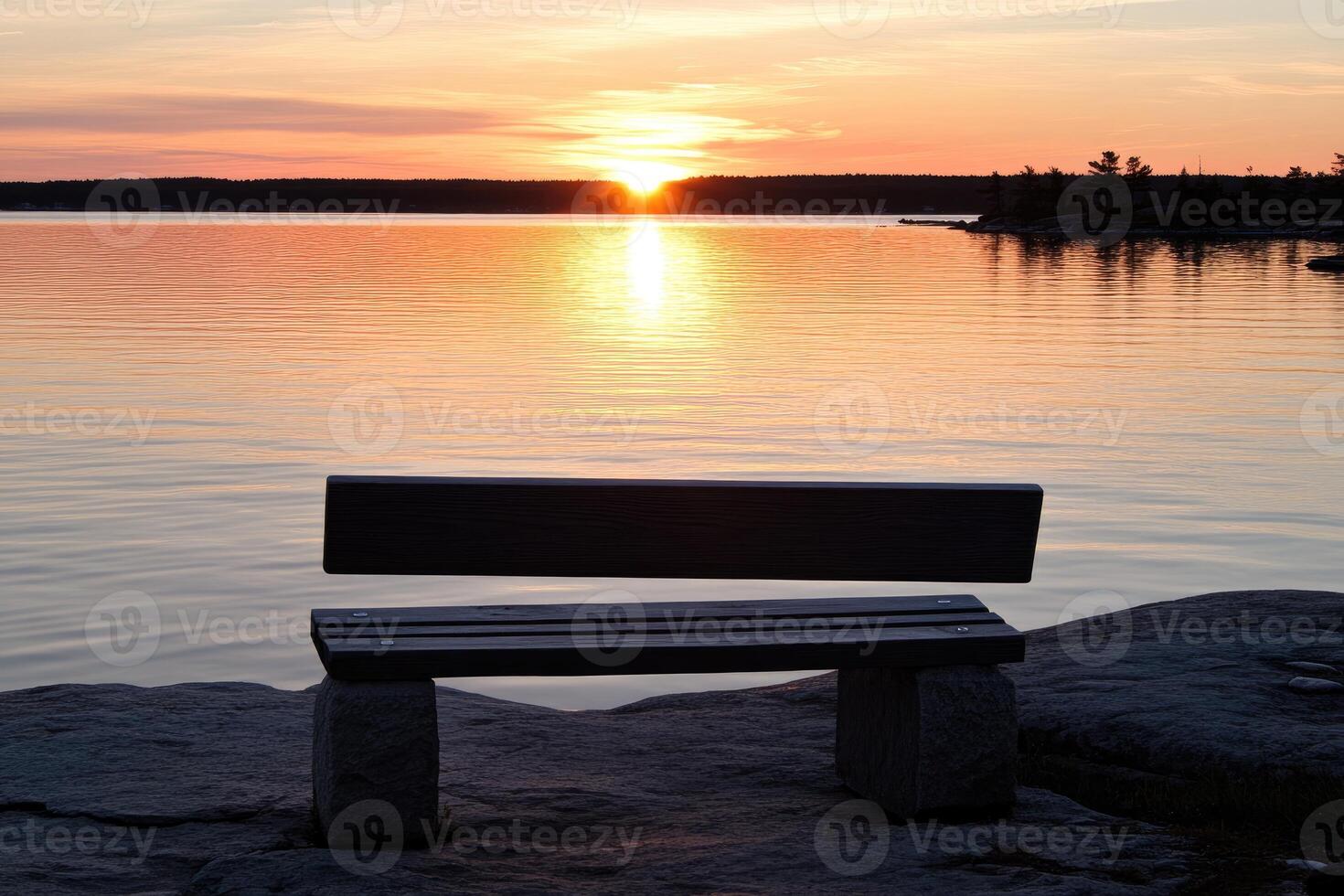 A bench sitting on a rock overlooking a body of water photo