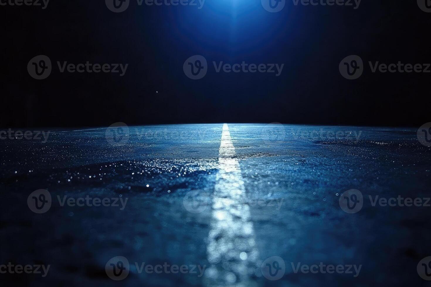 A dark road with a bright light shining in the distance photo