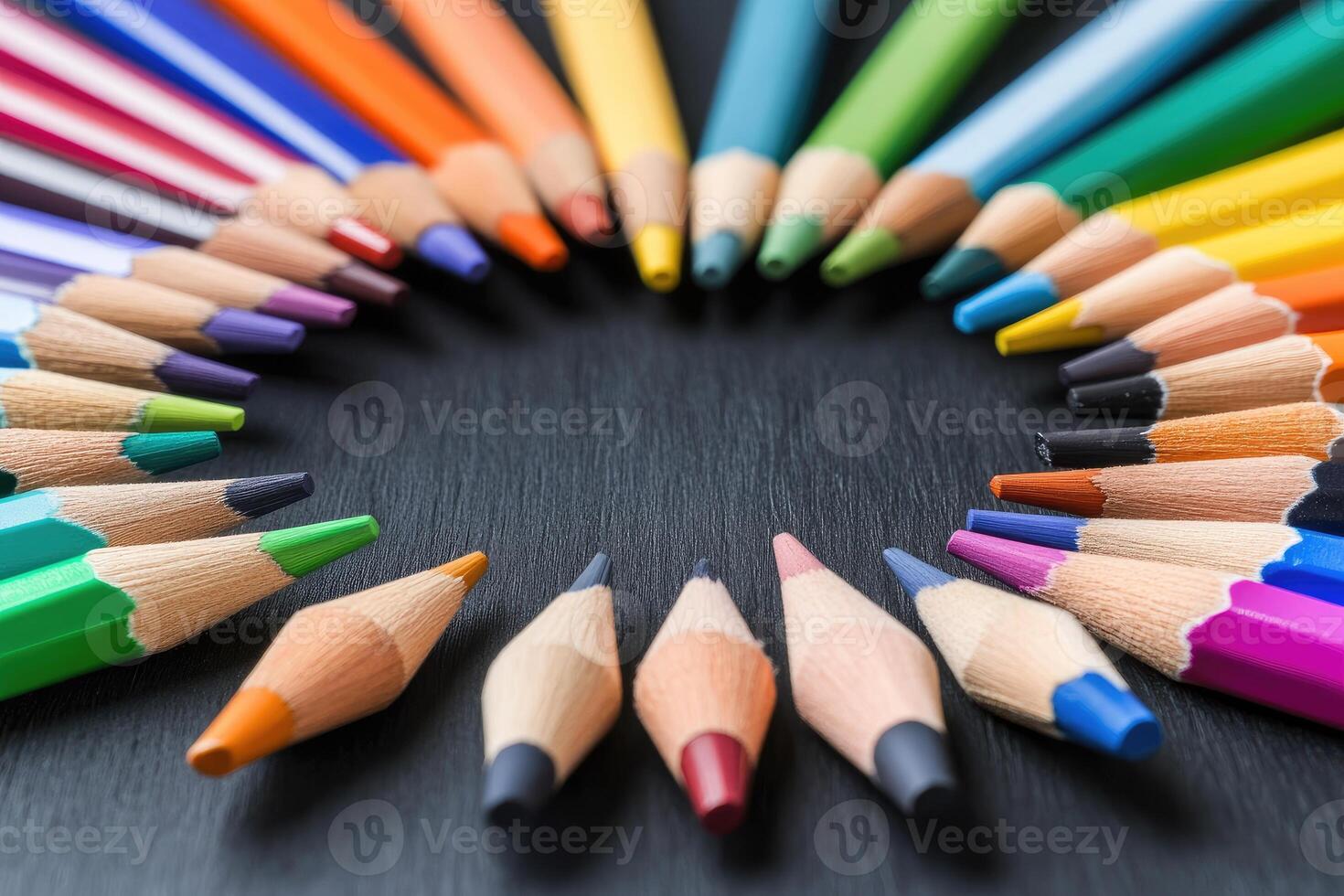Colorful pencils arranged in a circle on a black surface photo