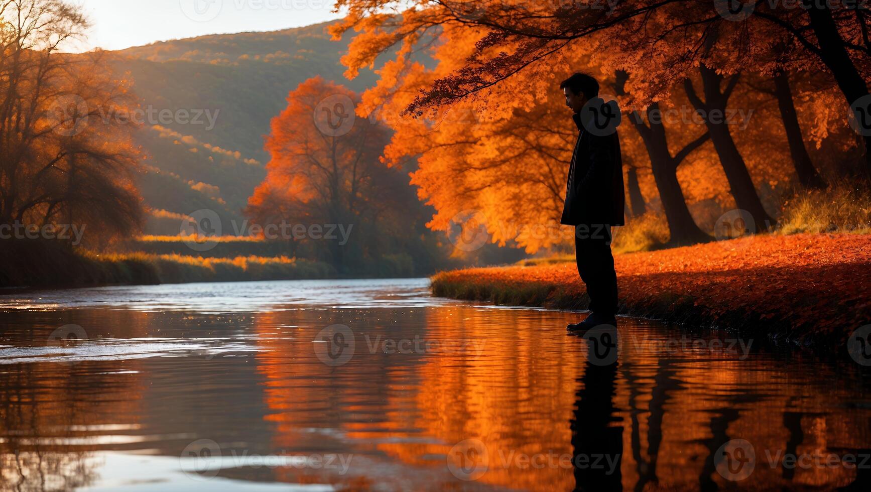 Man Contemplating by Autumn River with Golden Reflections at Sunset photo