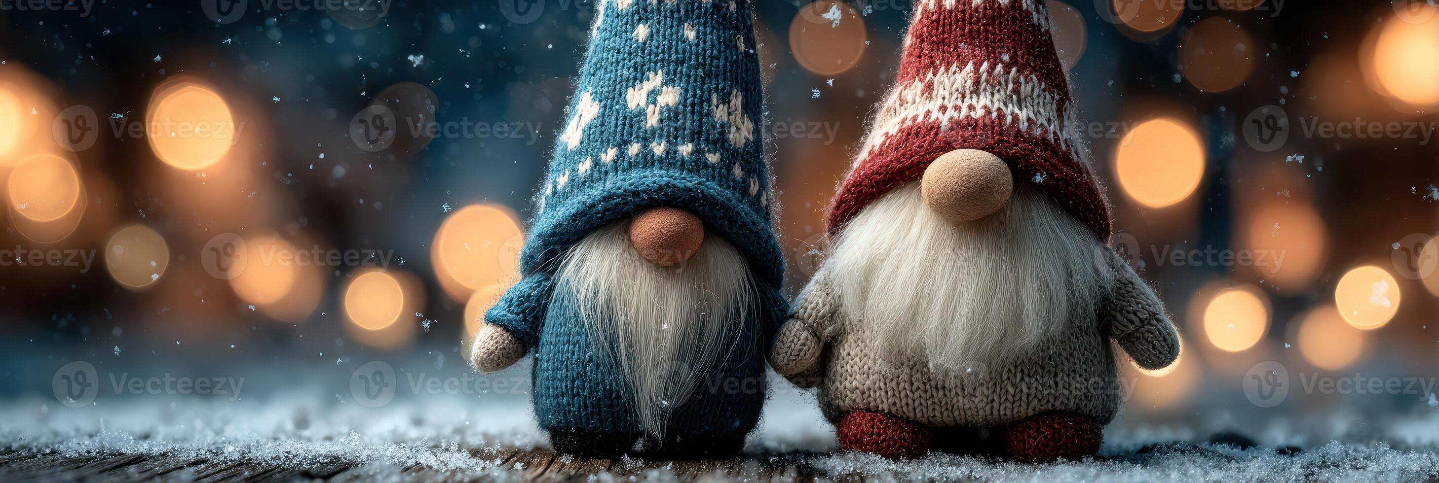 Two decorative gnomes wearing colorful knitted hats stand together in a snowy outdoor setting surrounded by soft, glowing lights photo