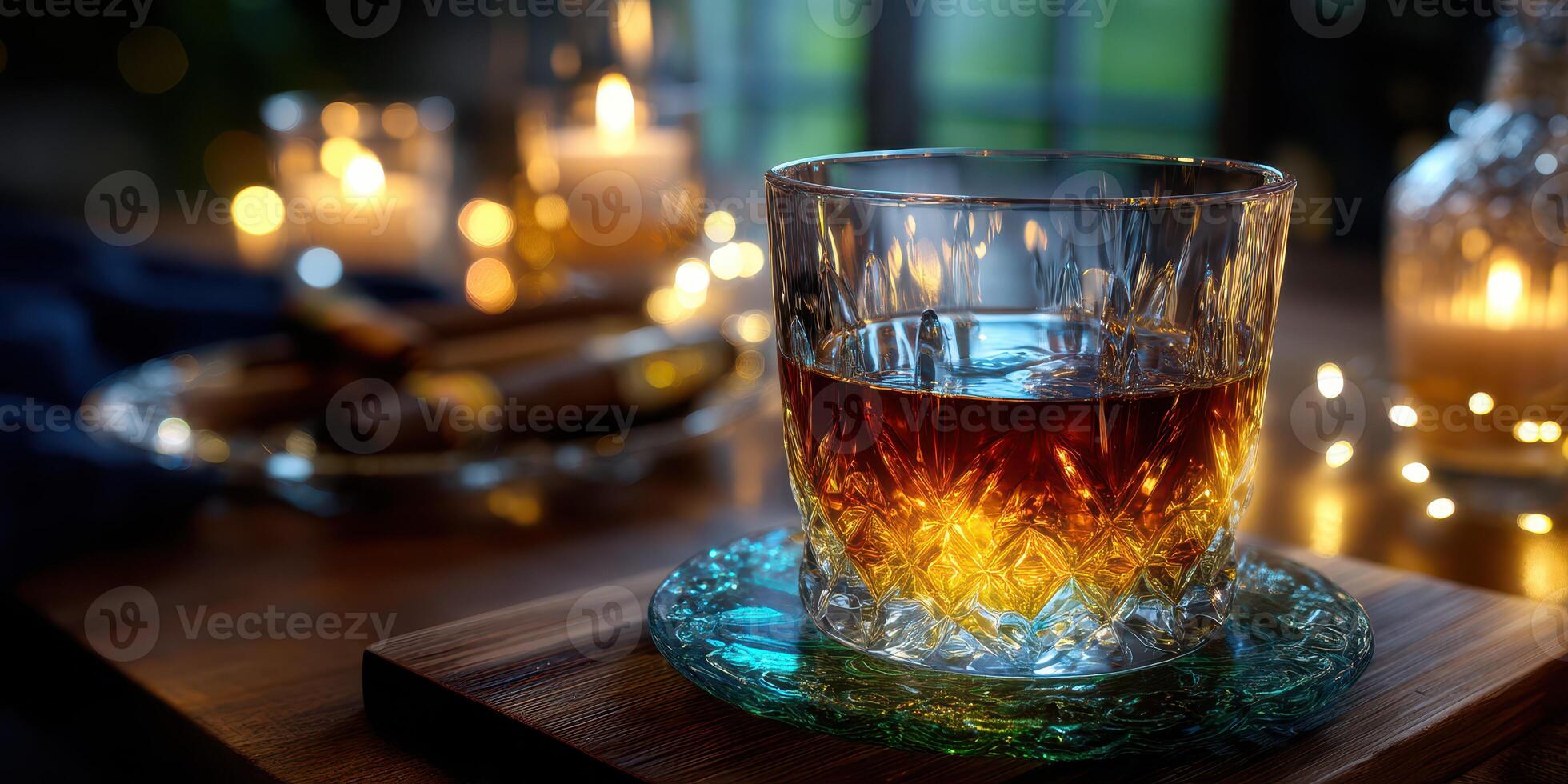 Whiskey in a crystal glass on a wooden table surrounded by candles and cigars at dusk photo