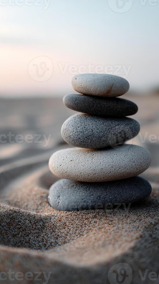Stacked smooth stones create a tranquil display on sandy beach at sunset photo
