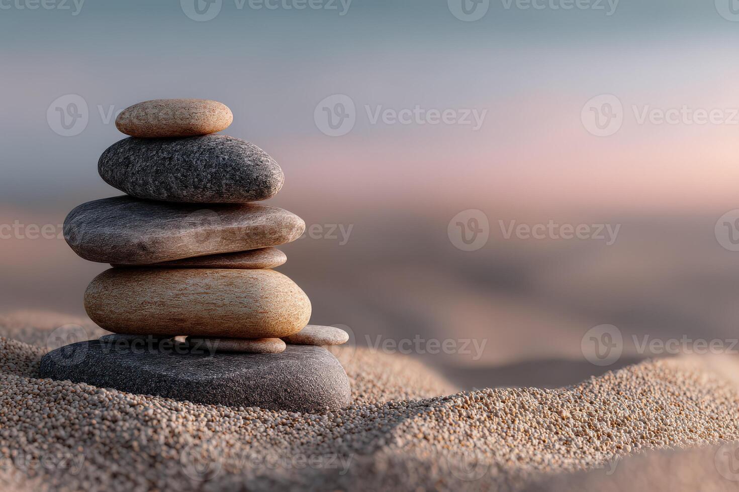 Balanced stones create a serene focal point on sandy beach during sunset photo