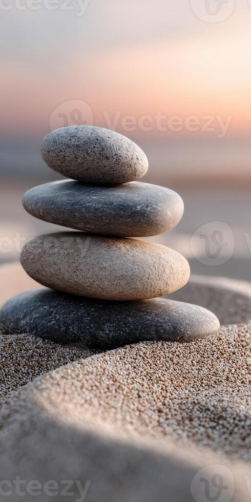 Four stones balanced on a sandy beach at sunset creating a peaceful scene photo
