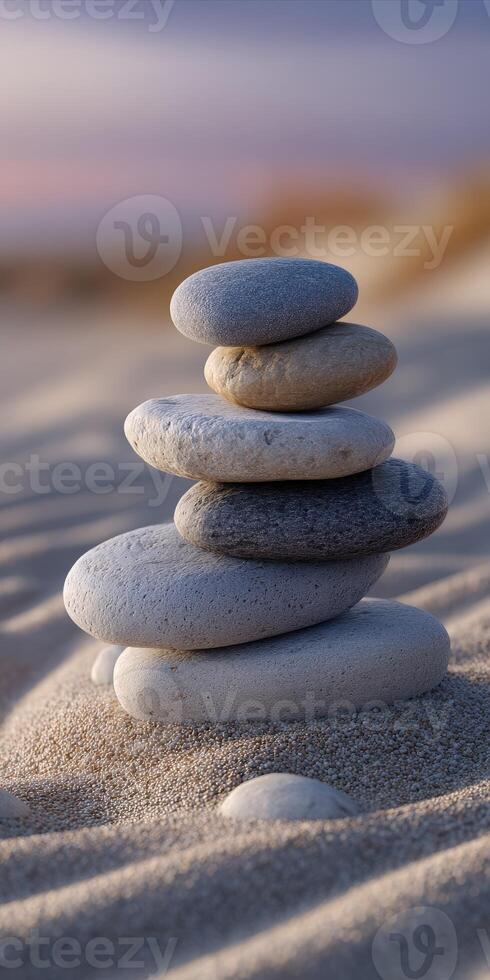Stones delicately balanced on sandy beach at sunset creating a serene atmosphere photo