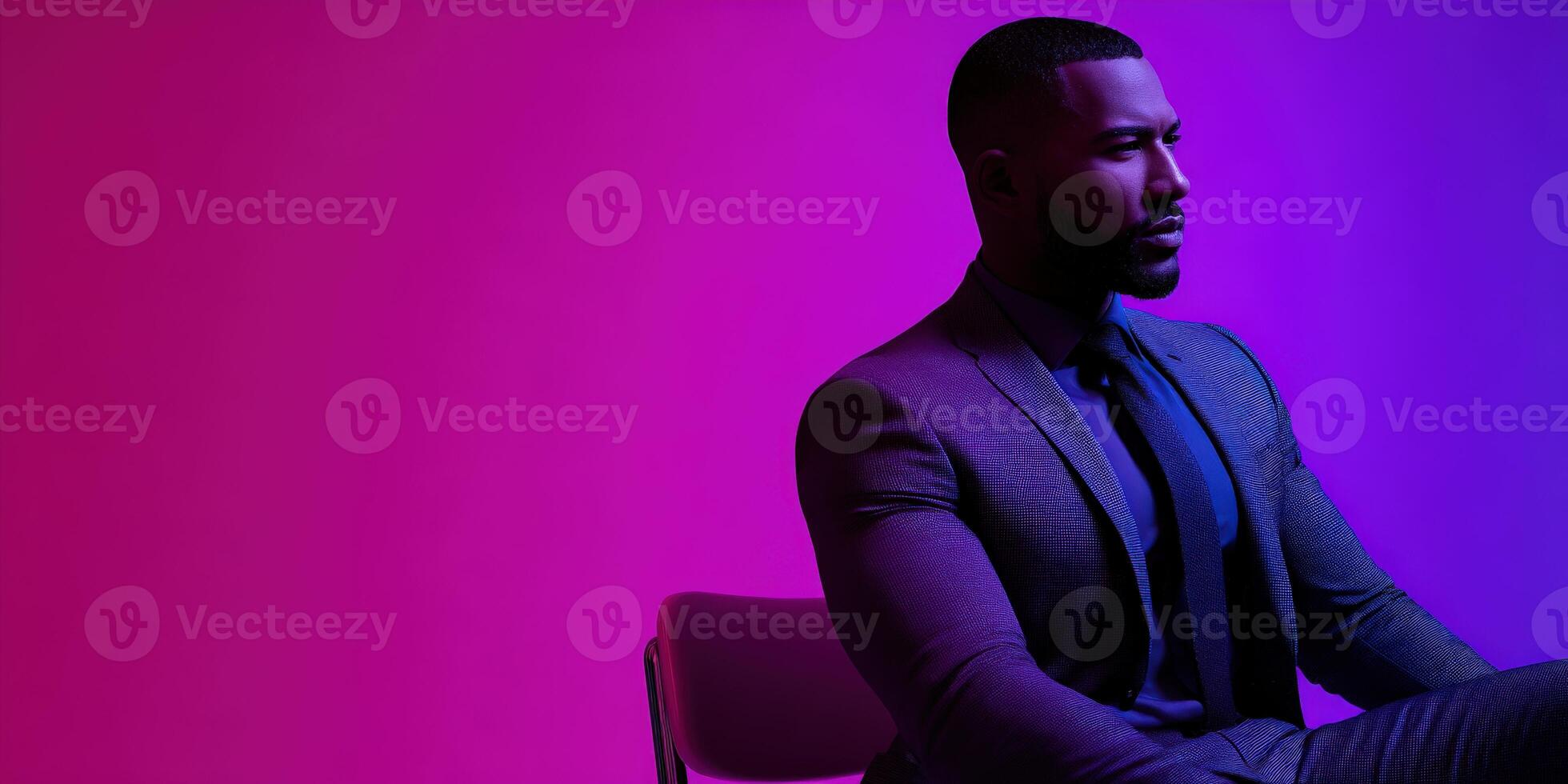 Confident man in formal attire seated against vibrant colored background photo