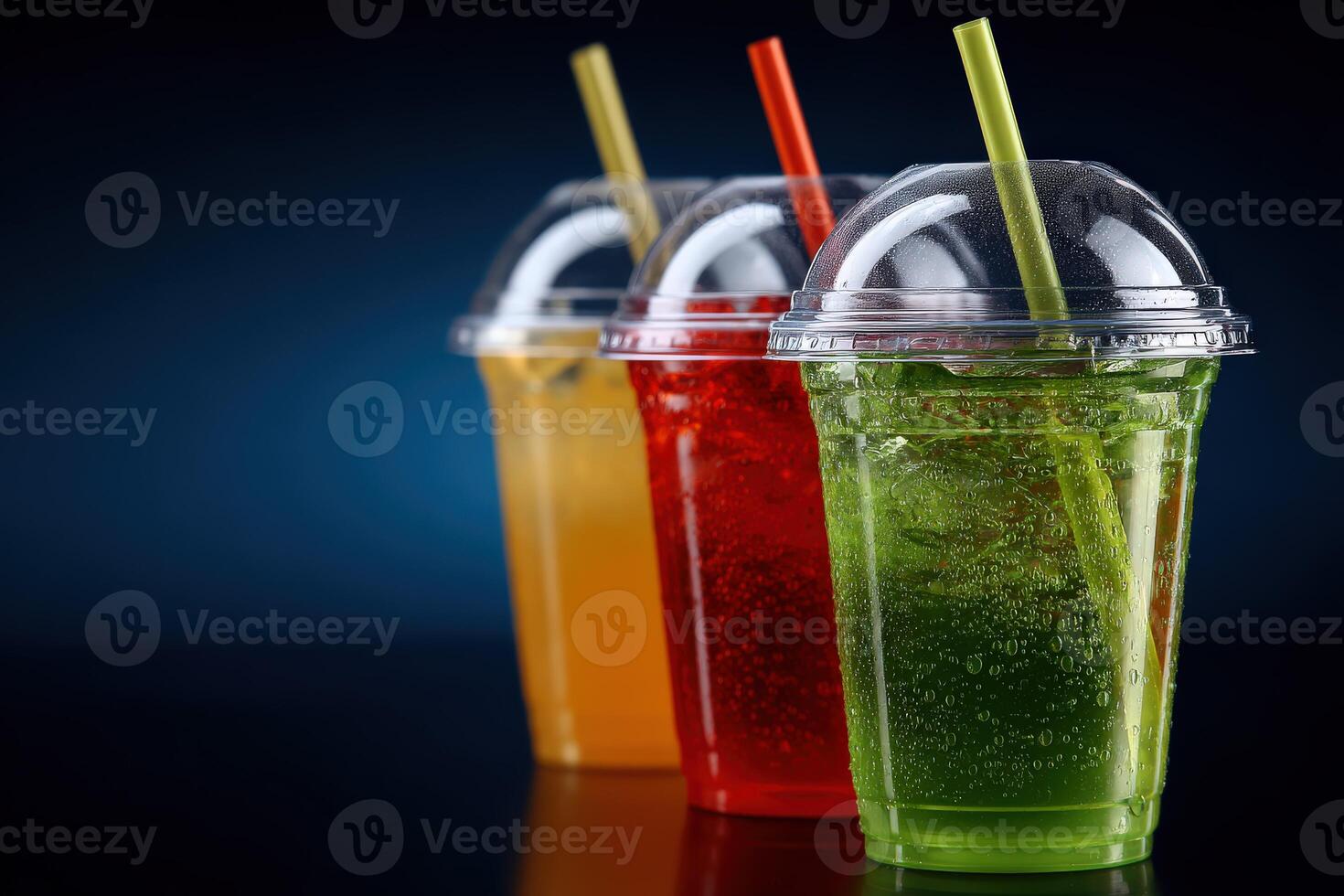 Colorful soft drinks in transparent cups with straws on dark background photo