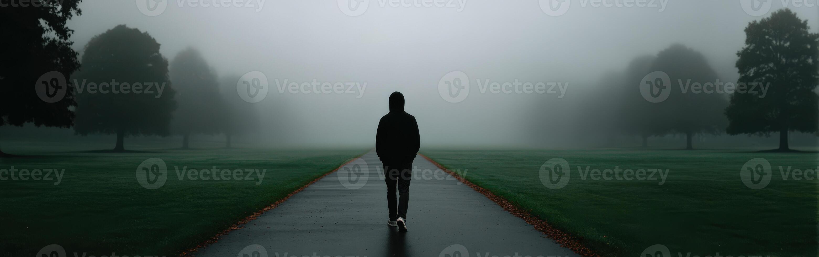Person walks alone on a foggy path in a tranquil park setting photo