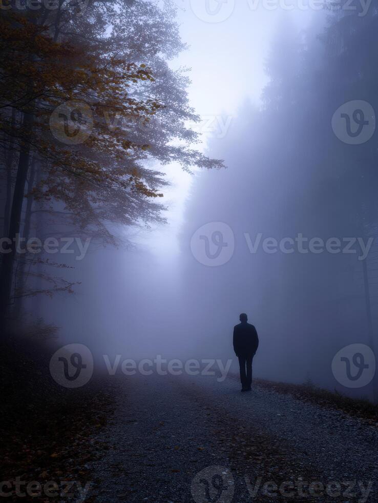 Mysterious figure walking along a foggy forest path in autumn photo