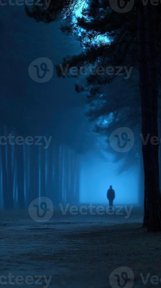 A man walking through a foggy forest at night photo