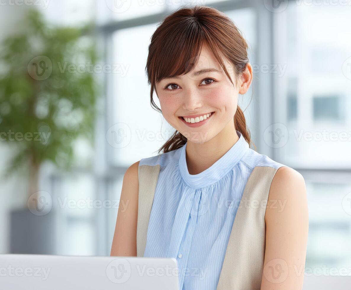 Young woman smiling while working on a laptop in a bright office space photo
