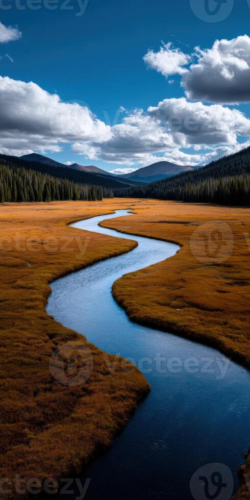 Serene winding river flows through golden valley amidst mountains photo