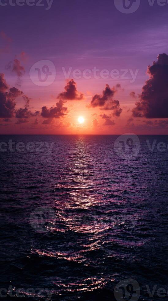 Sunset over ocean with colorful clouds and gentle waves in serene evening photo