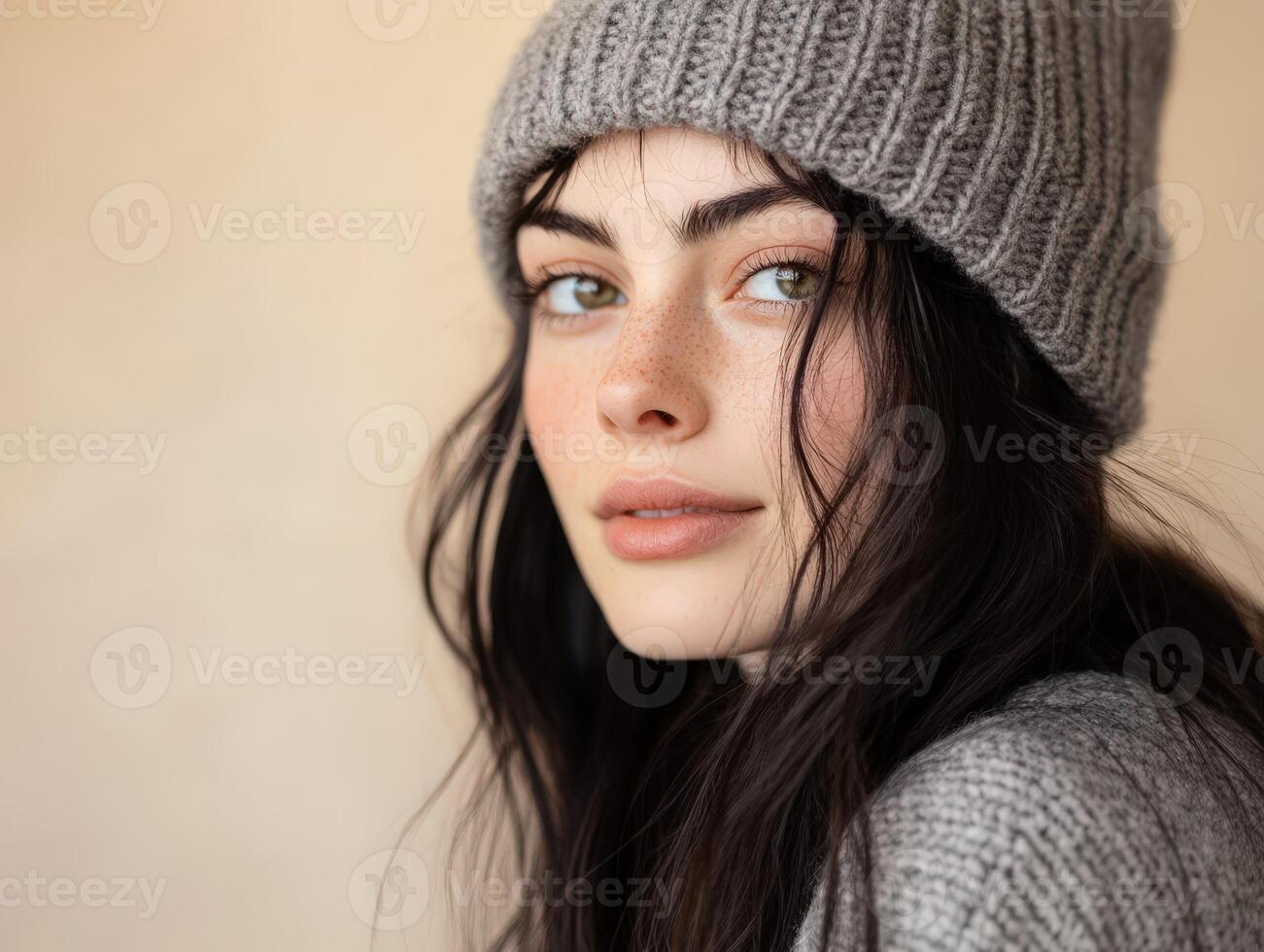 Young woman poses in grey knit hat and sweater indoors photo