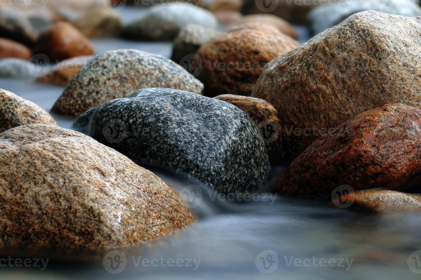 Gentle stream flows around colorful river rocks photo