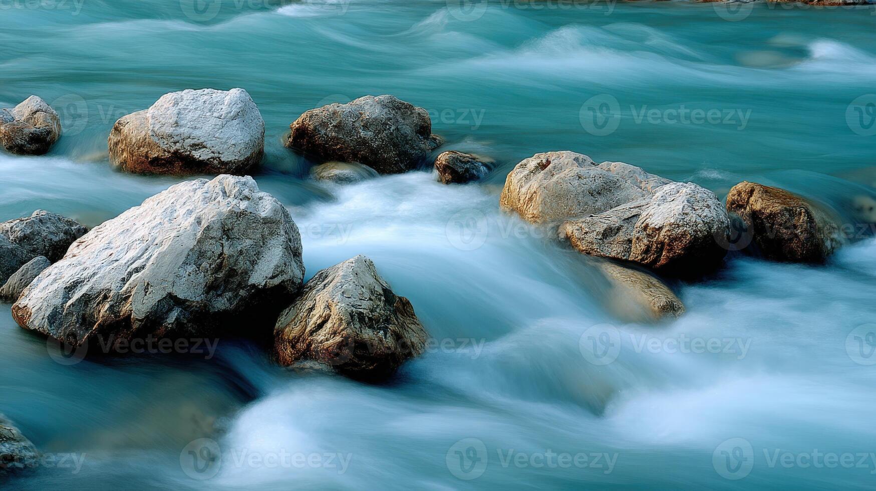 Fast flowing river water rushes past several large rocks photo