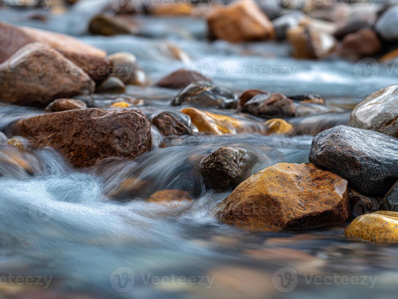 Mountain stream flows around rocks at daytime in Summer photo