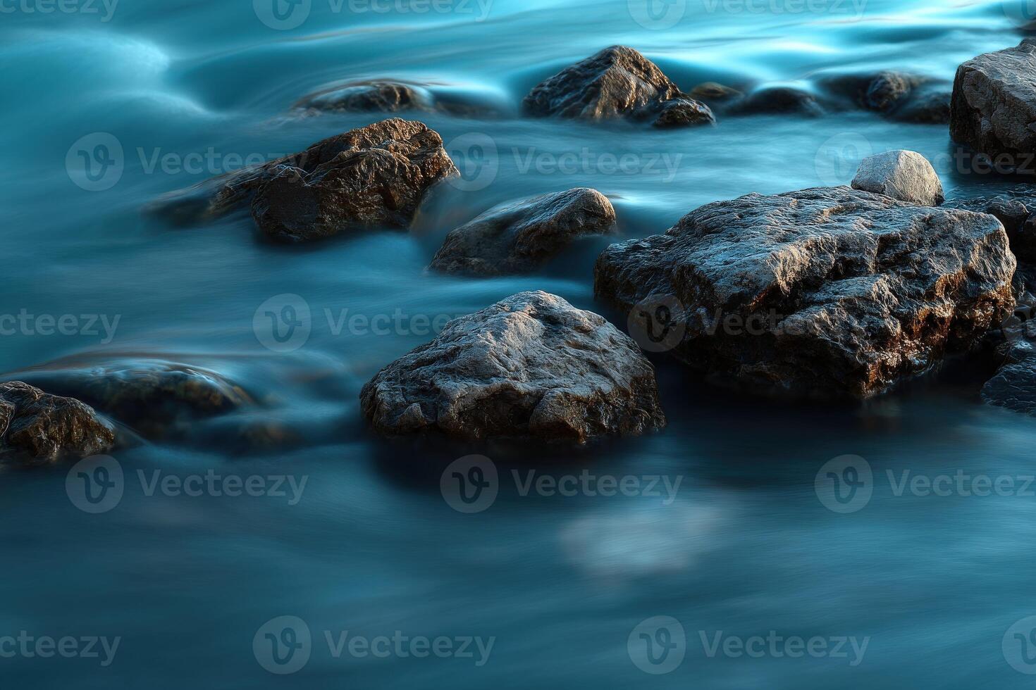 Water flows among large coastal rocks on the shore at sunset photo