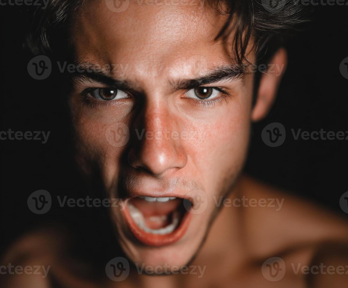 Young man with intense expression screams in dark lighting photo