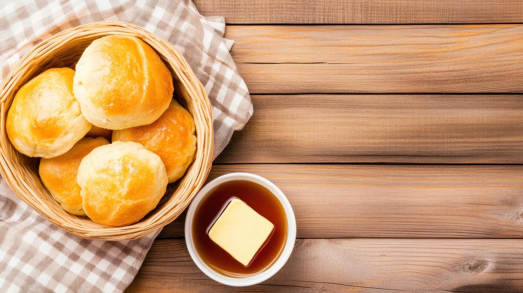 Dinner rolls in a basket, butter and syrup on a wooden table, for a family breakfast photo