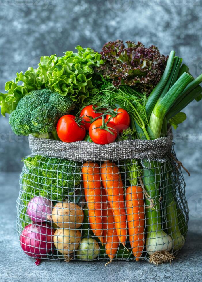 Veggies in a net bag, ready. A net bag filled with fresh vegetables such as lettuce, tomatoes, broccoli, and carrots rests on a textured surface. photo