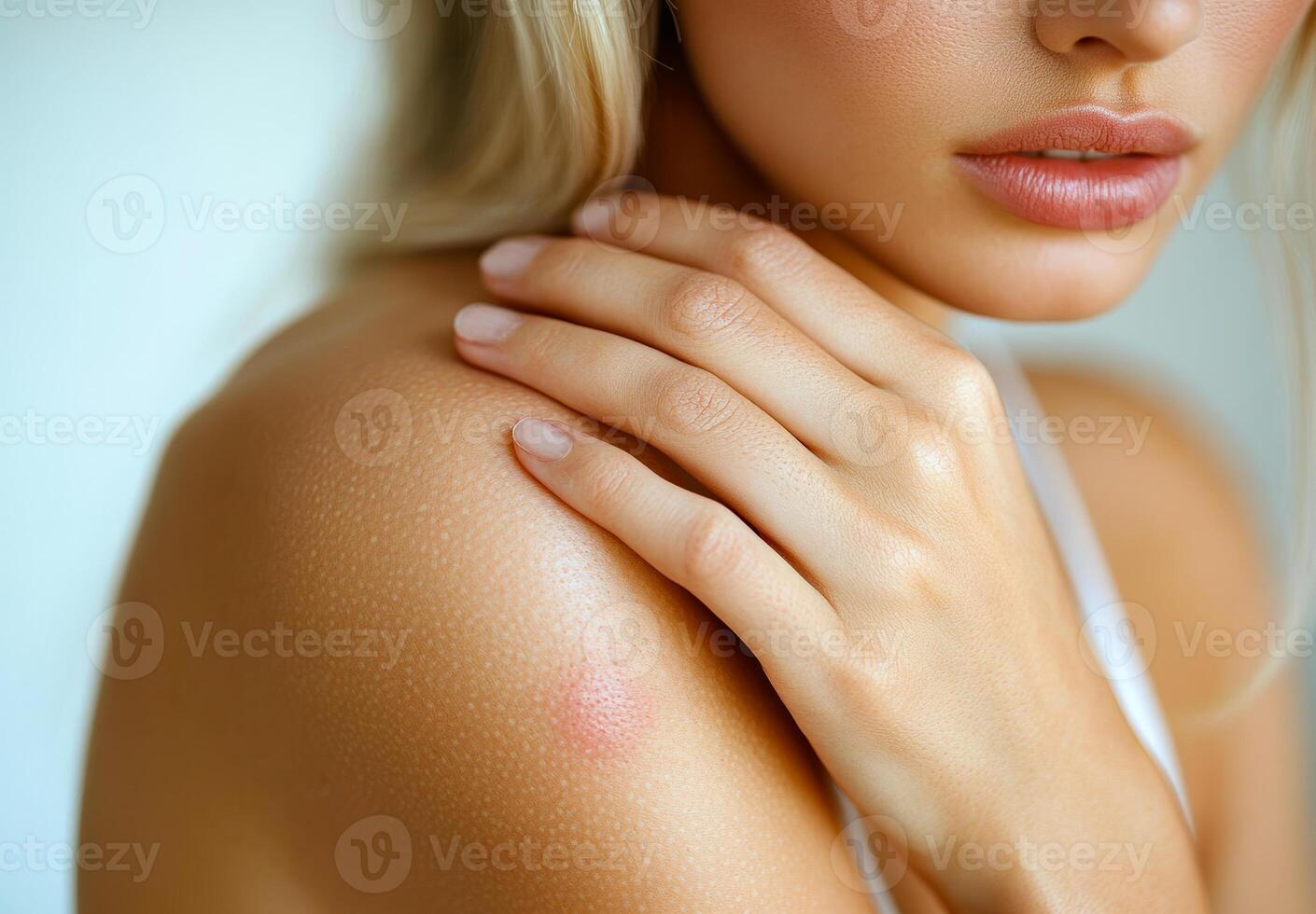 Close-up of natural skin beauty. Soft skin close-up showing a woman's shoulder and hand with natural textures and subtle freckles in bright light. photo