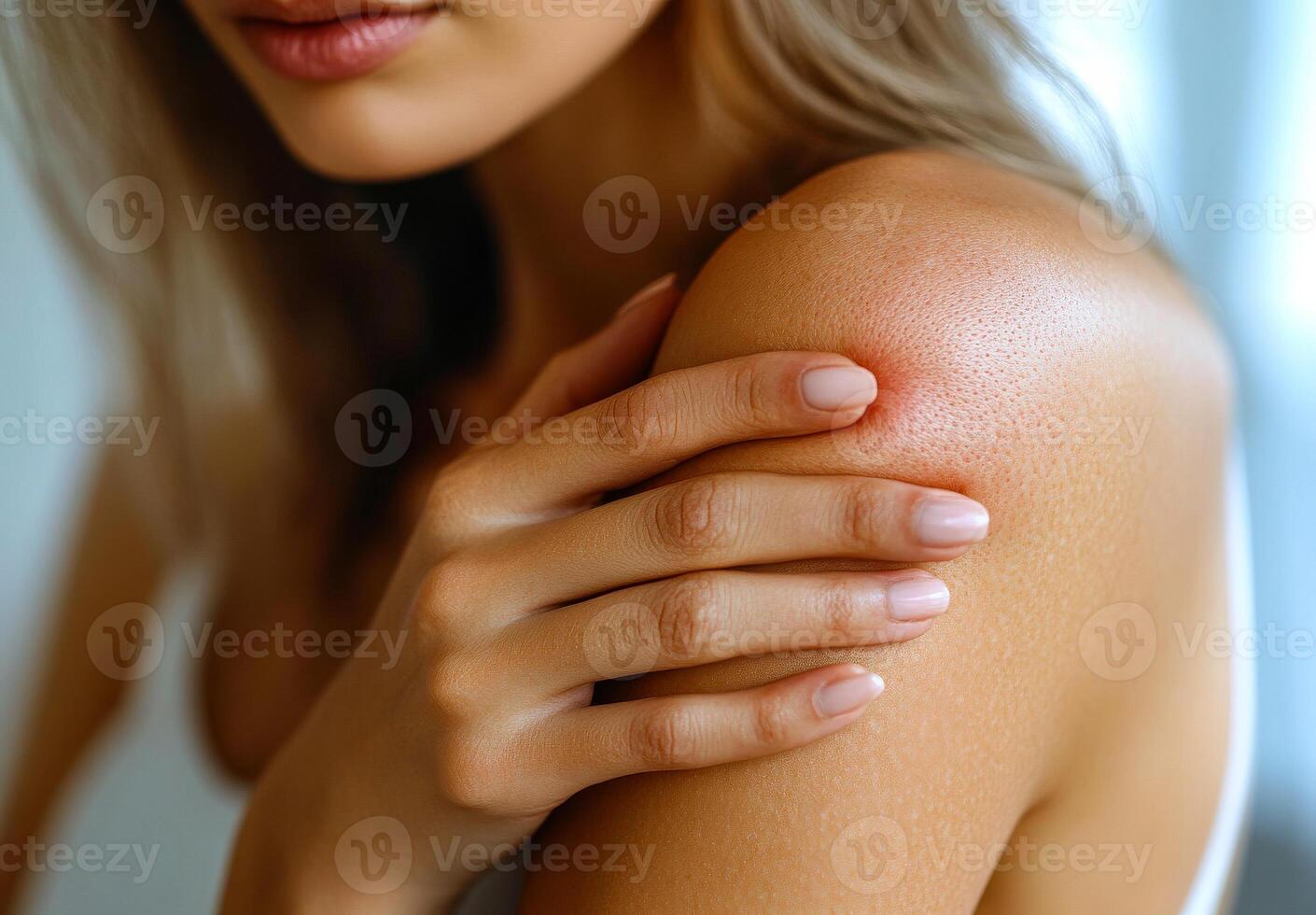 Caring touch on a healthy shoulder. A young woman gently touches her shoulder while looking thoughtfully, highlighting skin texture and care. photo