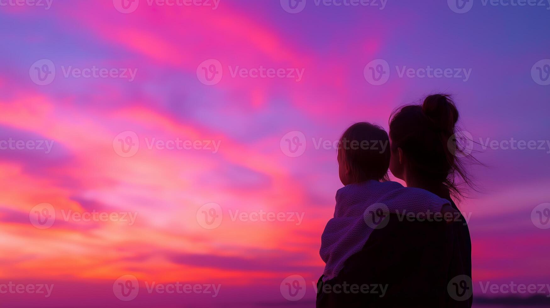 Mother and child enjoying a vibrant sunset by the beach during twilight photo