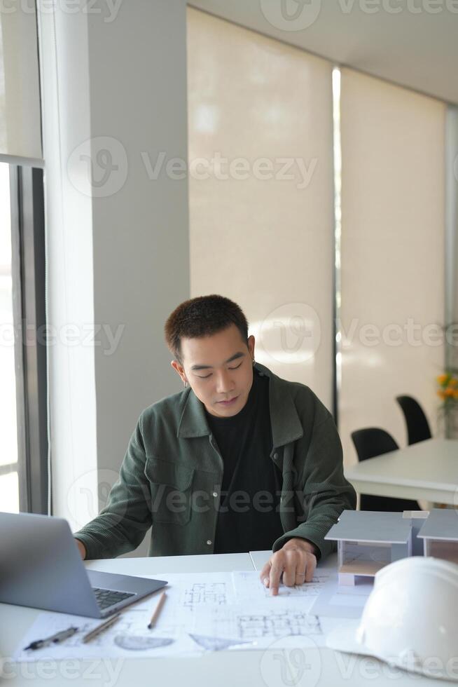 a man sitting at a table with a laptop and construction paper photo